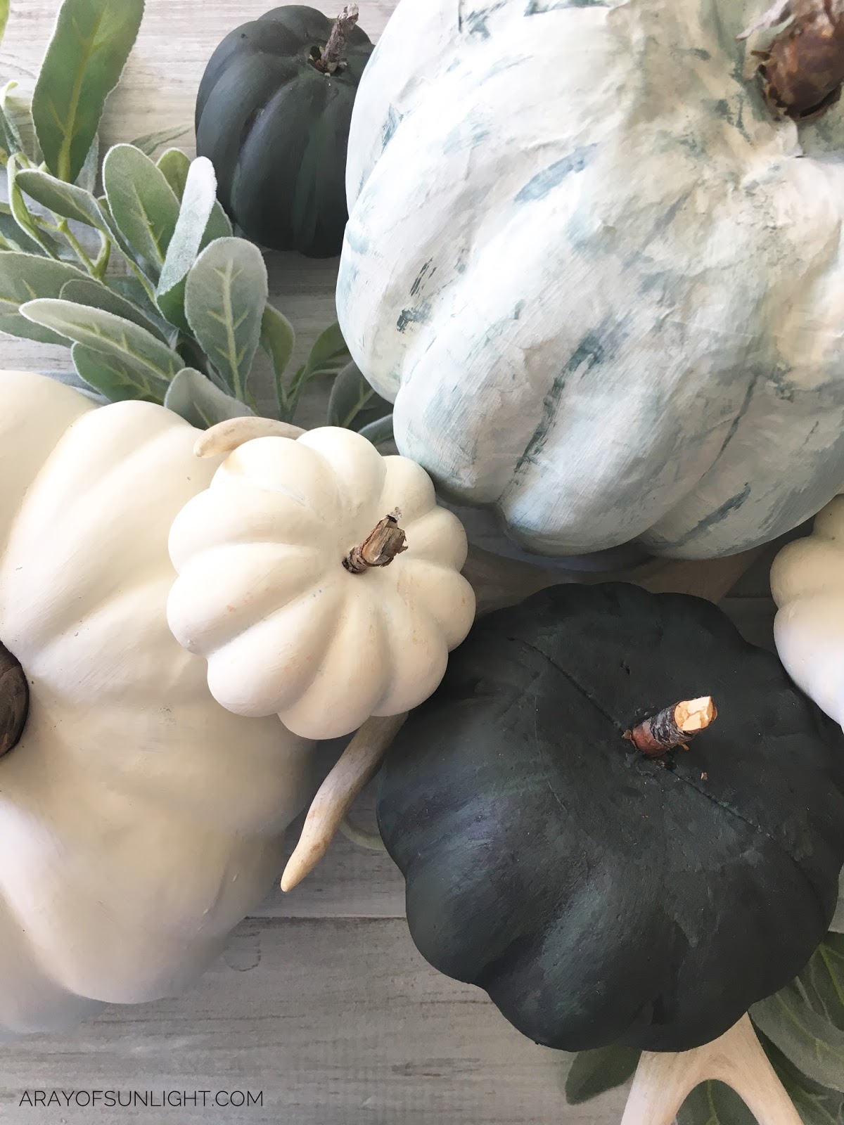 Learn how to make these painted fall pumpkins... the perfect project to get your fall decor going. We used Country Chic Paint to make these muted blue and green pumpkins and mixed them with lambs ear and antlers to go with our farmhouse decor. By A Ray of Sunlight