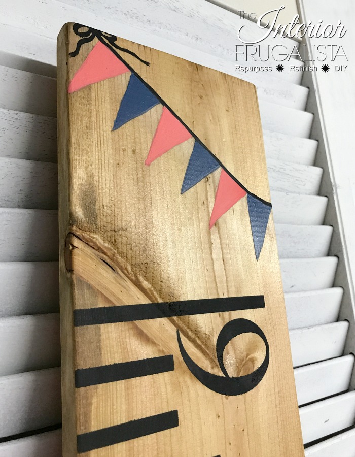 Personalized hand painted banner on the top of a pine board growth chart.