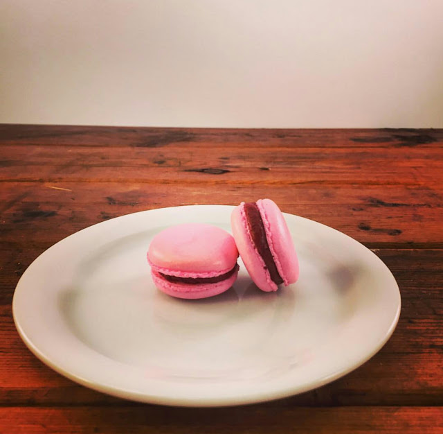 Strawberry Cream macarons on a white plate on top of a wooden table background