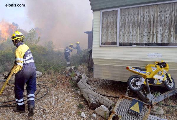 Vivienda económica próxima a las llamas Bomberos españoles atacando un incendio forestal