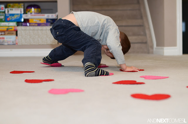 Child with hands and feet on red and pink felt hearts as part of a Valentine's Day gross motor activity Child with hands and feet on red and pink felt hearts as part of a Valentine's Day gross motor activity