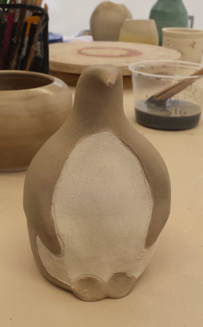 Raku pottery penguin in progress, with terra sigillata applied.