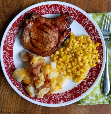 dinner plate with cheese and bacon potato bake, pork chop and corn