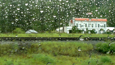 looking out a rain drop covered window on a western railway, saloon and hotel