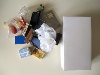 COllection of dolls' house miniature purchases piled on a desk.