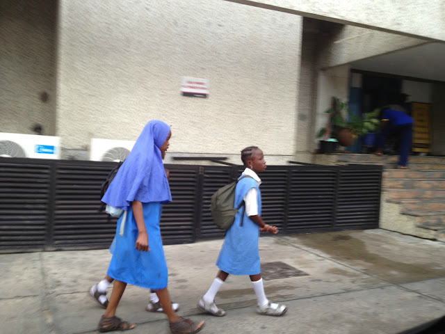 Nigerian children walking to school past an office building