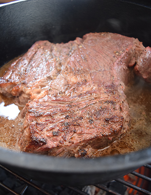 Braising a chuck roast in a dutch oven on the grill breaks down the connective tissue into fork tender beef.