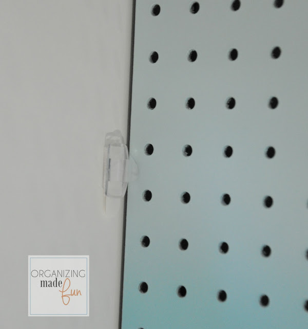Use light clip with velcro strip to hold back pegboard panel :: OrganizingMadeFun.com
