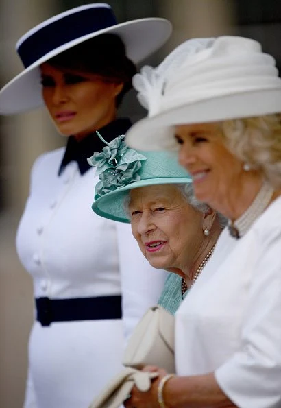 Melania Trump is wearing a custom white crepe dress with navy details by Italian fashion house, Dolce & Gabbana. Queen Elizabeth