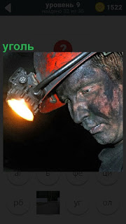На шахте шахтер осуществляет добычу угля в каске и фонарь на голове
