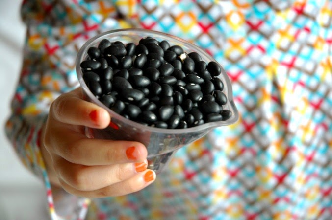 child holding cup of black beans