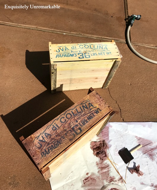 Two crates on patio, one stained with paint, one unfinished