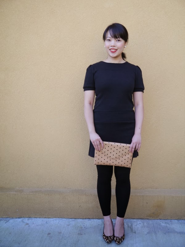 Little black sweater dress worn with black leggings, leopard print pumps, pearl stud earrings, red lipstick, and a black-and-tan polka dot clutch.