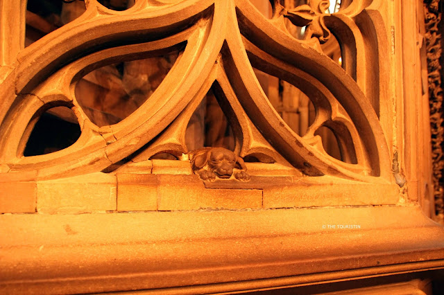 Stone sculpture of a small dog below the window of a cathedral