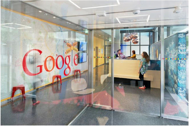 Ein Foto zeigt ein Bild aus einem Google Büro. An einer Glaswand ist das Google Logo angebracht