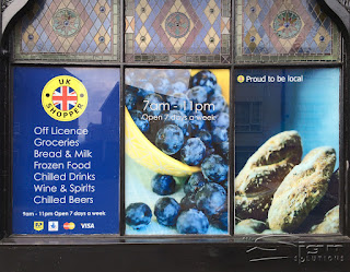 UK Shopper three window stickers with a soild background, the other two windows have large pictures of blueberries falling out of a bowl and freshly cooked bread.
