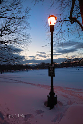 street light in snow silhouetted against pink and blue sunset