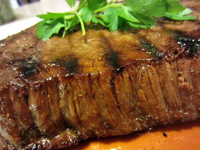 Killer London Broil by Renee's Kitchen Adventures ready to slice, still whole, on plate with parsley garnish