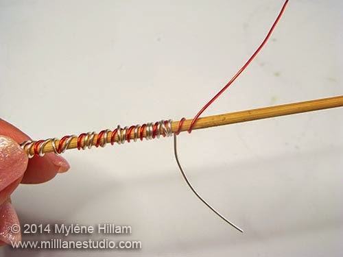 Wrapping the silver wire around the skewer twice in between each red coil.