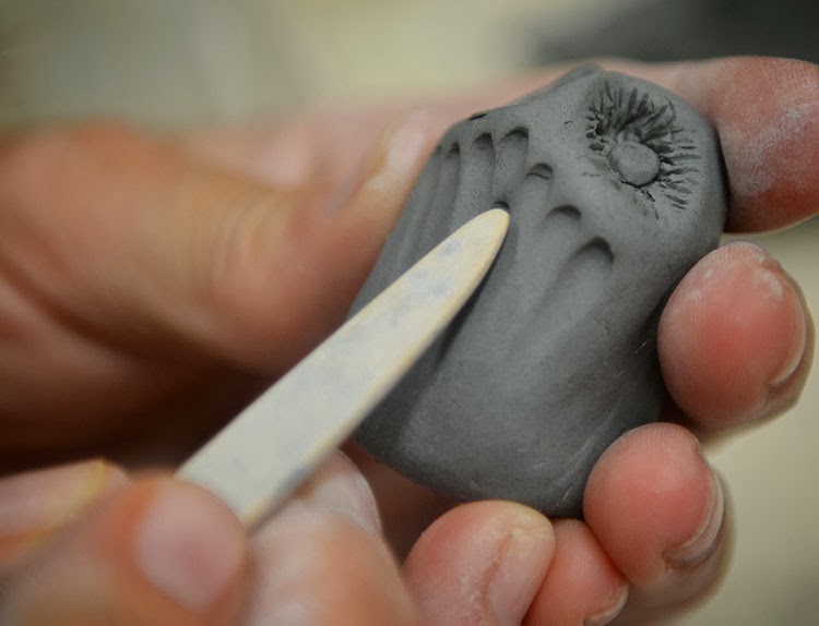 Creating chest feathers on a clay owl with the wooden end of a clay loop tool.