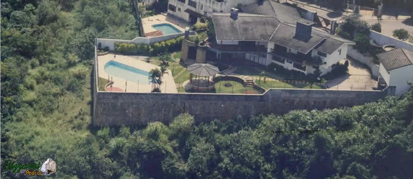 Construção da residência com construção da piscina com esse muro de arrimo com pedras com até 7 m de altura pois o proprietário queria que a construção da piscina ficasse no mesmo nível do piso da residência. Executamos o quiosque com telhas com a execução do paisagismo.