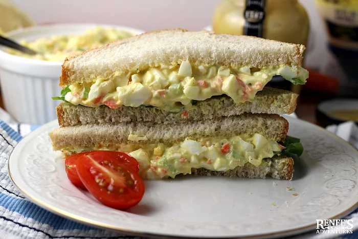 Cut and stacked egg salad sandwich on a white plate