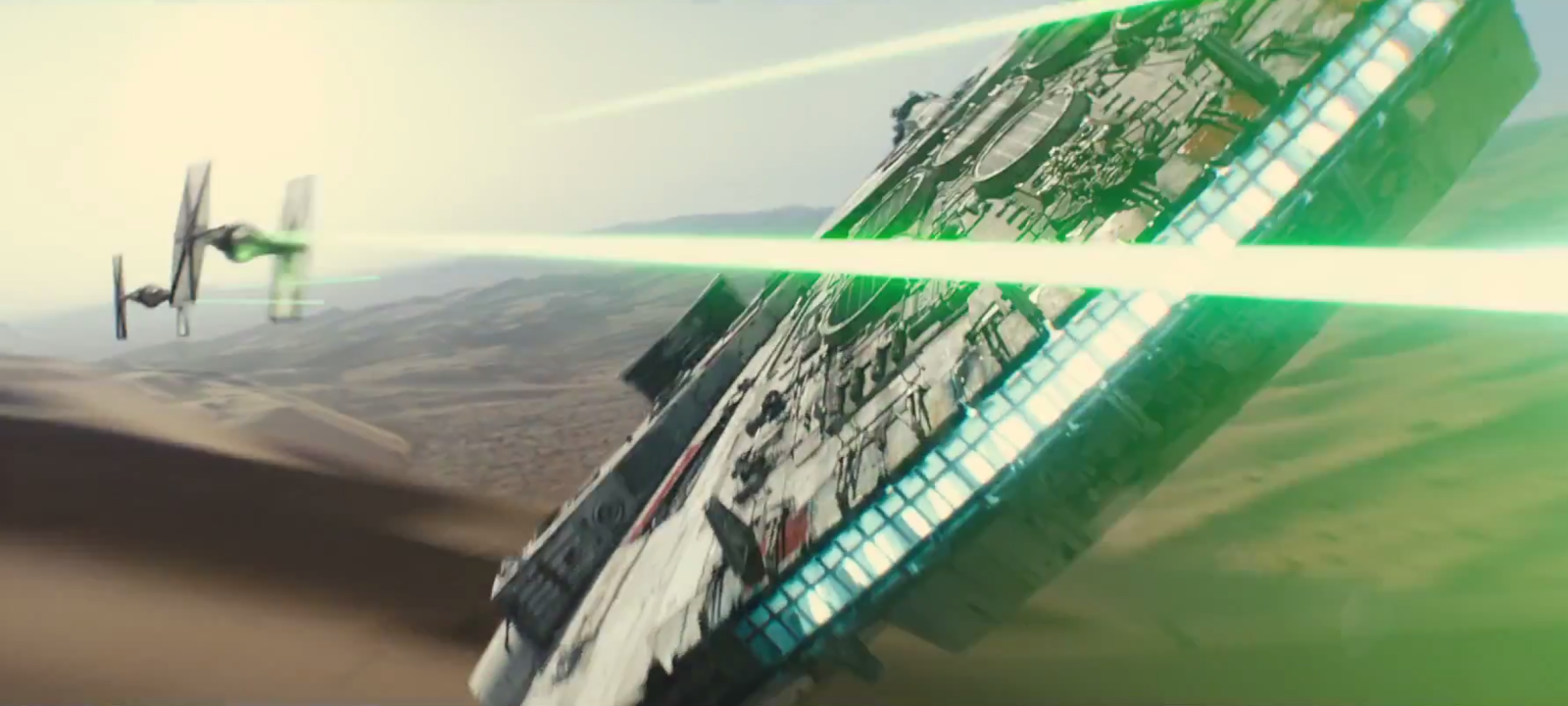The millennium Falcon flying along the desert floor while engaged with Tie-fighters