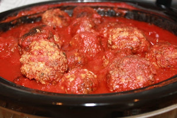 Meatballs, sauce in a black pot simmering