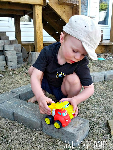 Child driving toy cars along DIY play roads in the backyard