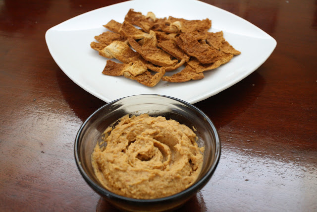 A bowl of hummus with pita chips on the side.