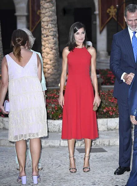 scoop neckline sleeveless fit and flare red dress. Dolce & Gabbana ready-to-wear collection, gold clutch. Queen Sofia