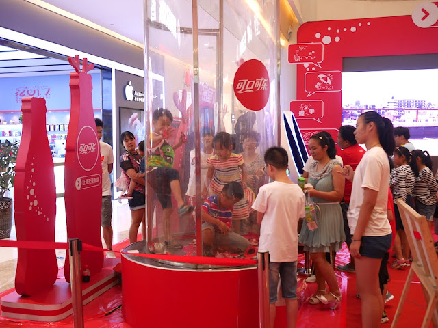 kids in a money blowing machine at a Coca-Cola promotion