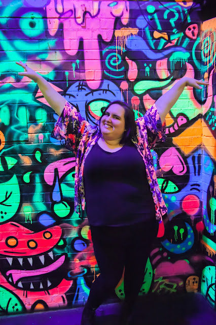 Samantha Nicole standing in front of a graffiti wall