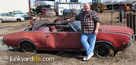 Keith Lively proudly stands by his latest hot rod project, a red 1969 Cutlass convertible,
