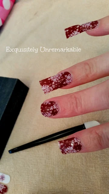 Applying red floral nail wraps on fingers