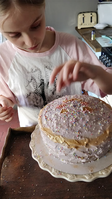 child decorating a rainbow birthday cake