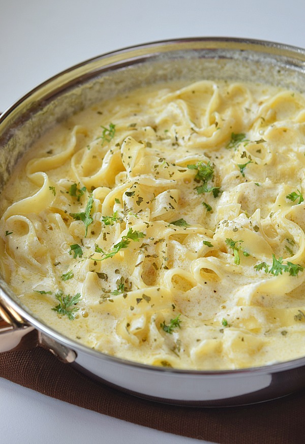 a pan with creamy Fettuccine Alfredo with lots of grated Parmesan