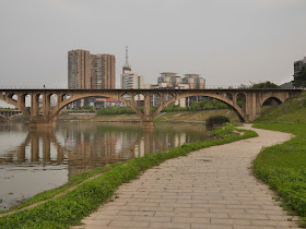 brick path alongside a river and a person walking on a bridge crossing a river in Hengyang