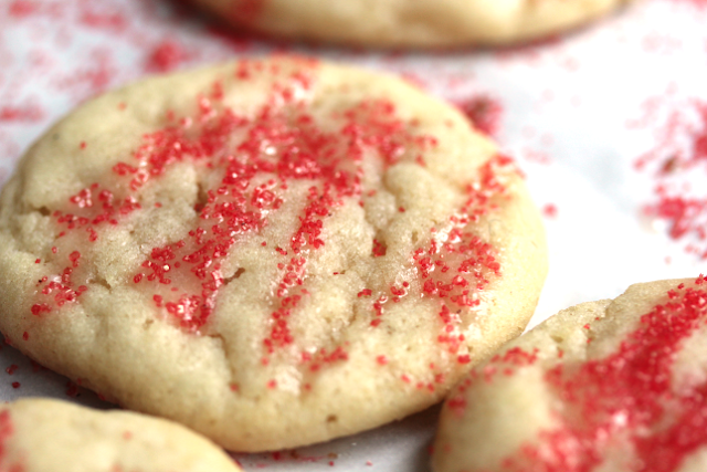 Close up shot of an eggnog iced butter cookie with red sprinkles drizzled on top. 