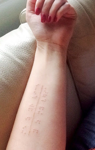 O branco da tinta da tatuagem sente em Braille