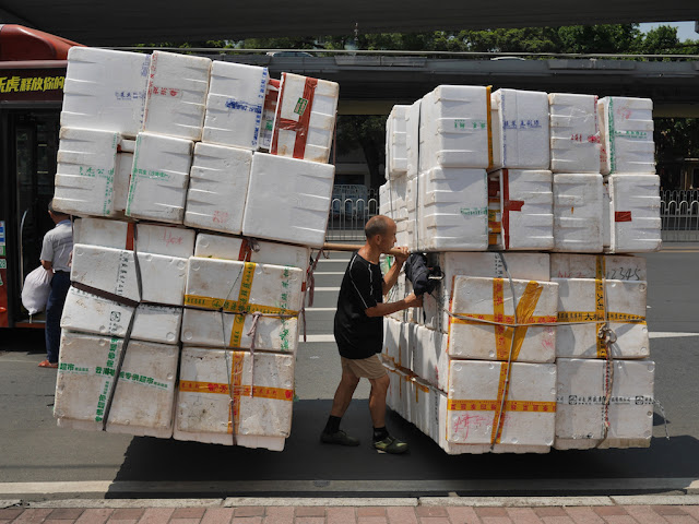 man carrying many styrofoam containers at once in Guangzhou