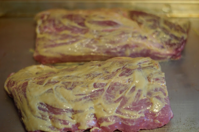 Mustard being rubbed onto the baby back ribs.
