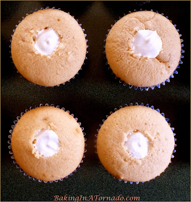 Fluffernutter Cupcakes, reminiscent of a favorite New England sandwich. A peanut butter cupcake with a marshmallow fluff center. Add a chocolate frosting, and you've got dessert. | Recipe developed by www.BakingInATornado.com | #recipe #cupcake