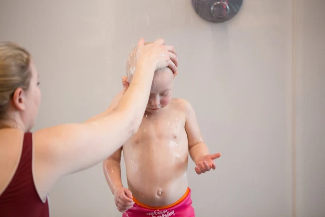 A baby in the shower having her hair washed