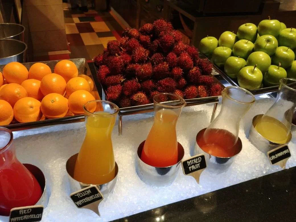 Fresh orange, rambutan, green apples, and fruit juices at the dessert station of The Grand Kitchen