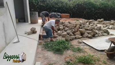 Bizzarri trabalhando, fazendo o corte das pedras moledo para fazer o revestimento de pedra na parede, com pedra moledo na cor bege com espessura de 15 a 20 cm.