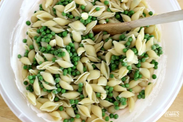 Pasta shells and peas sitting in large bowl with spoon