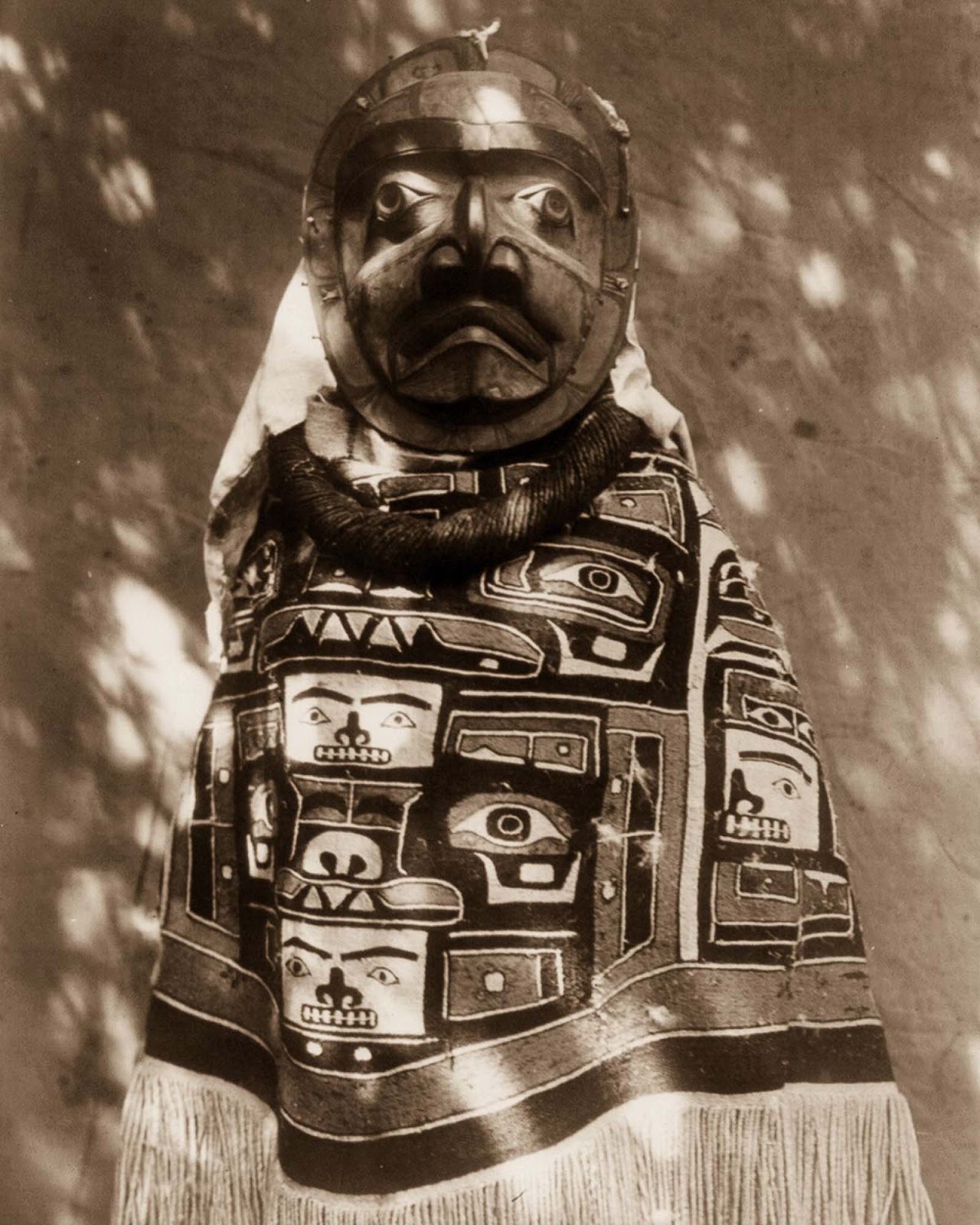 A Qagyuhl woman wears a fringed Chilkat blanket and a mask representing a deceased relative who had been a shaman. 1914.