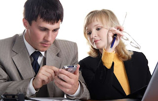 Una pareja mira la pantalla de un celular.