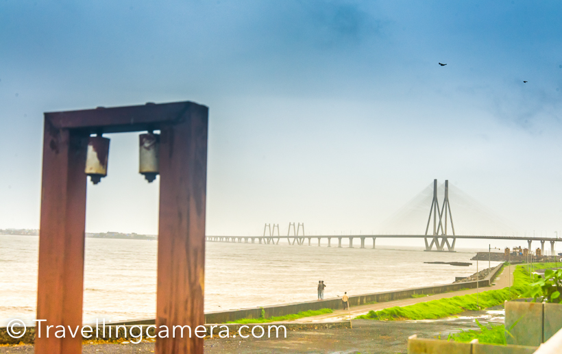 When in Mumbai, we drove around few of the popular places in Mumbai and Travellingcamera visited Sea-link twice in 2 days and loved shooting here. Sea Link connects old Mumbai with new city. This Photo Journey shares more photographs of Sea Link and places from where this beautiful bridge is viewed and clicked.I was staying at JW Marriot near Airport and didn't want to go to other side of Mumbai city  and there is a toll at beginning of Sea Link. So we went till the beginning of Sea Link and took u turn from left after clicking few shots of sea, sea link and high-rise buildings on other side of the sea.I was not happy with what I clicked at this place, so planned to come again but overall all the photographs in my opinion are average. I have seen some of the stunning photographs on web but then realized that I needed to know more about the geography of the place and what makes the best choice to shoot Sea Link.The weather was rainy and it was hazy all around. I clicked some of these plain shots of high-rise buildings on other side of the sea.After taking u turn before the sea link starts, we went to bandstand. After little disappointment about Shahrukh Khan's house at Bandstand, we headed towards Taj LandsEnd and came across these amazing views of Sea link. This certainly is beautiful place to shoot Sea Link and I was imagining how the bridge would look in night when lights on the bridge shine.Next day, plan was to visit Gateway of India and we had to cross the Bridge, so we planned to stop our cab again. Light was a little better, but there was hardly any scope of moving around and trying different things and we were in little hurry.Now we had to cross the bridge, but stopping the cab on bridge was not allowed and our driver strictly conveyed the same to us. So we calmly sat on the back seat and made our cameras to shoot while driving.As we hit the bridge, it started raining heavily and now wiper was also running on the front glass. So we had to manage our clicks in such a way that we shoot front view without much distraction :)Mumbai rains are crazy and very unpredictable. That was one of the main reason that we booked the cab for whole day. It was my first attempt to book Ola cab for whole day and it was not so bad, like my earlier experience with Ola.Overall it was fun driving around Bandra-Worli sea link and clicking these photographs. I wish to spend more time in Mumbai and understand these places in better way.
